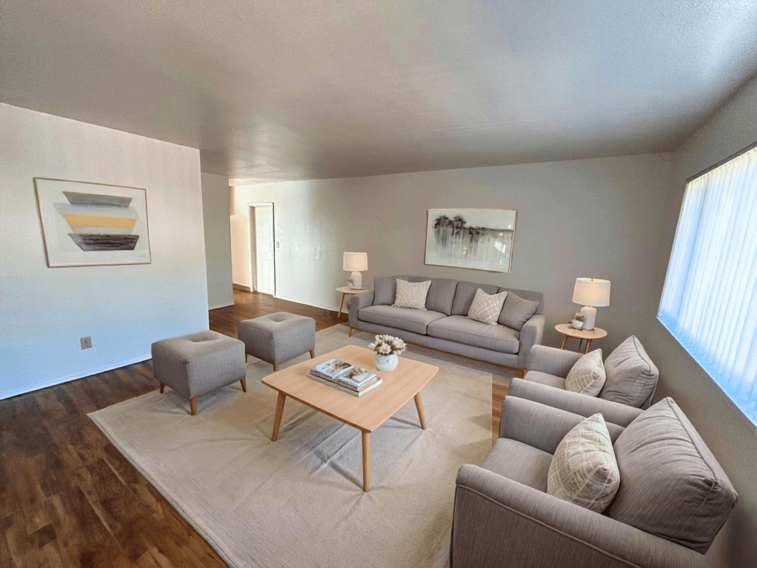 A living room with a grey couch, a coffee table, and a painting on the wall.